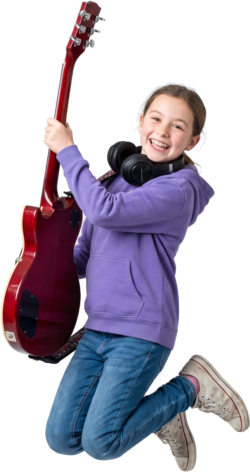 A student with headphones jumping mid-air, guitar in hand, grinning