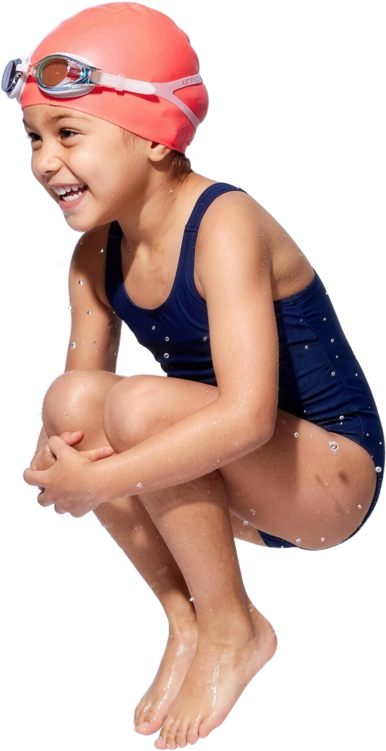 A laughing child in a coral swim cap tucked into a cannonball, mid-air above the pool